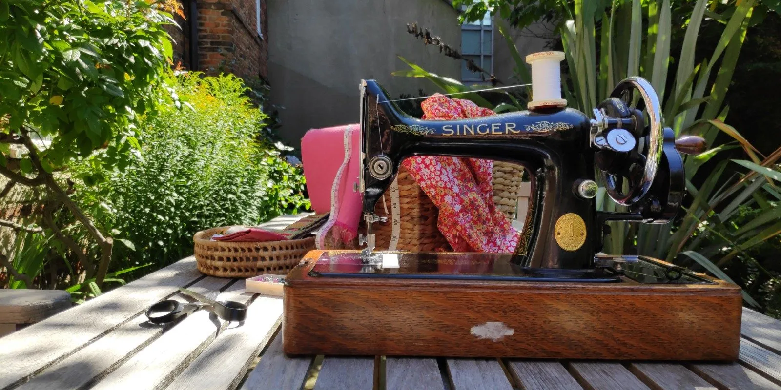 Sewing 2 An antique sewing machine, scissors and fabric on a table in a garden symbolising the author's resilience