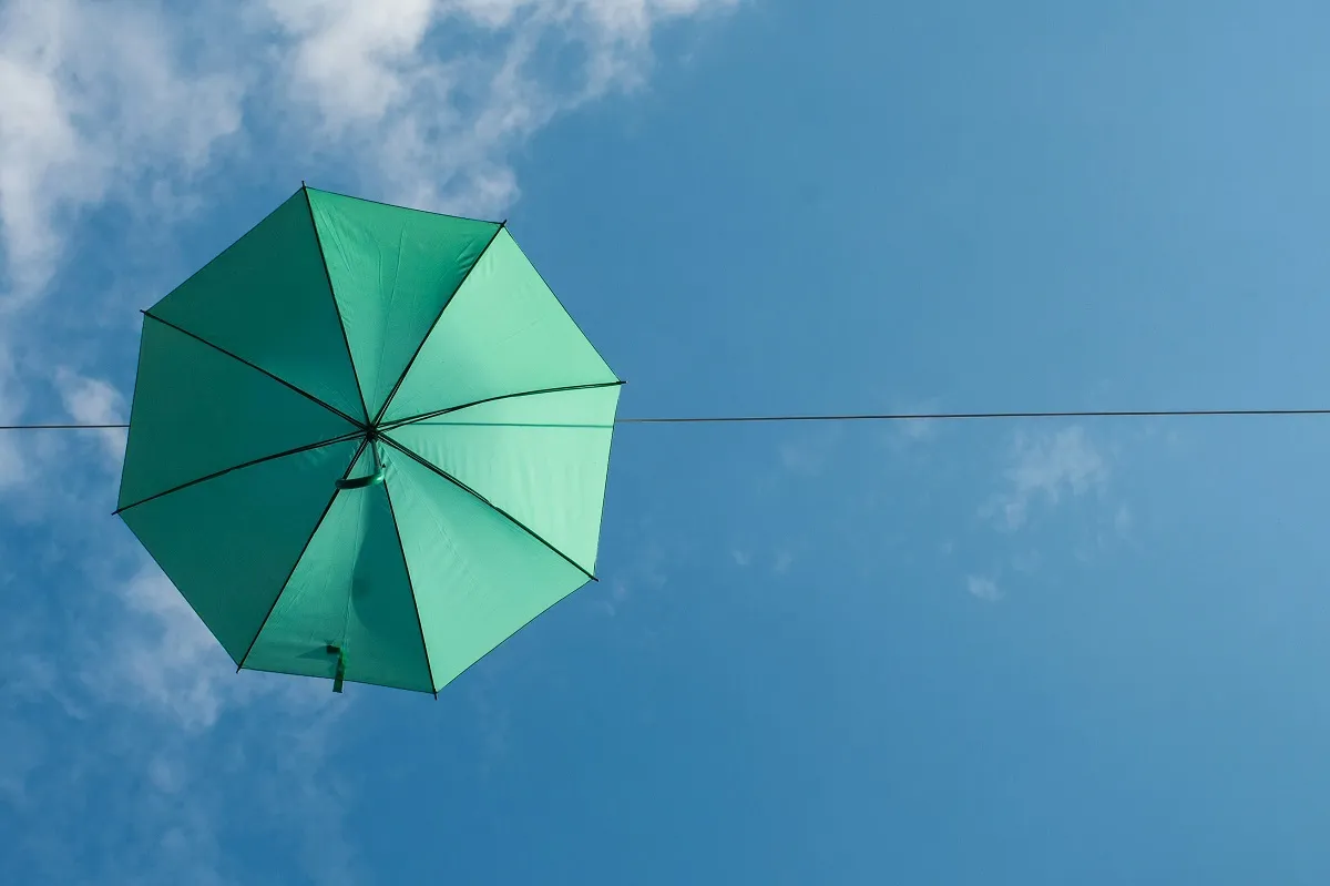 alessandra-caretto-TeD6G8xvo0M-unsplash 1200 Green umbrella against a blue sky with white cloud signifiying building resilience